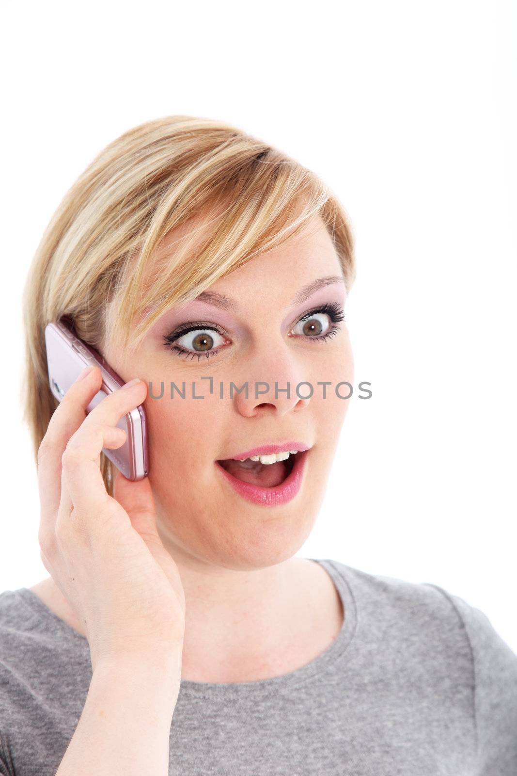Pretty young woman talking on her mobile phone and reacting in amazement to good news isolated on white Pretty young woman ttalking on her mobile phone and reacting in amazement to good news 