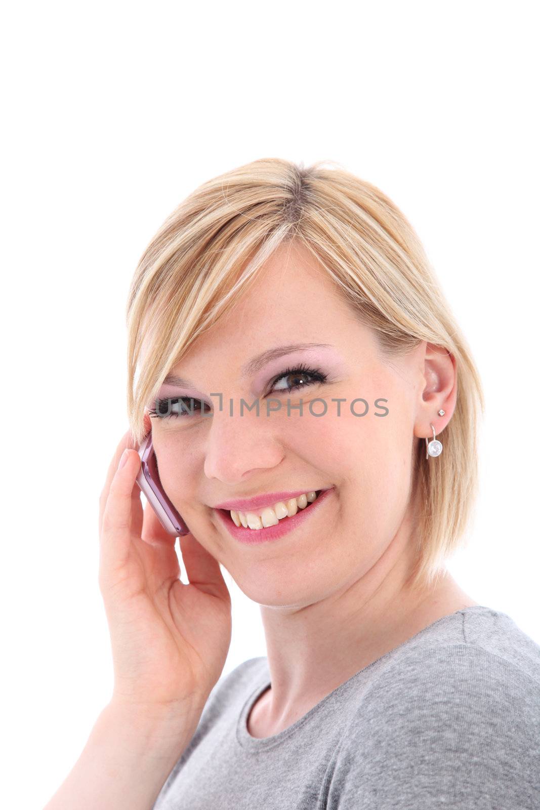 Happy woman smiling in pleasure as she chats on her mobile phone isolated on white 