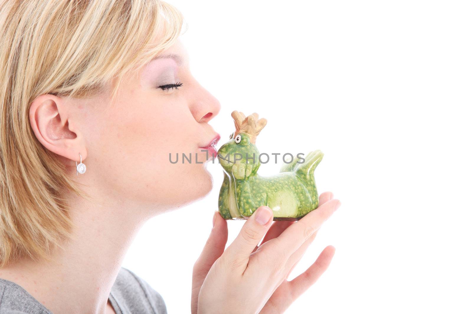 Beautiful woman fantasising with her eyes closed as she kisses her frog hoping for a fairy tale prince