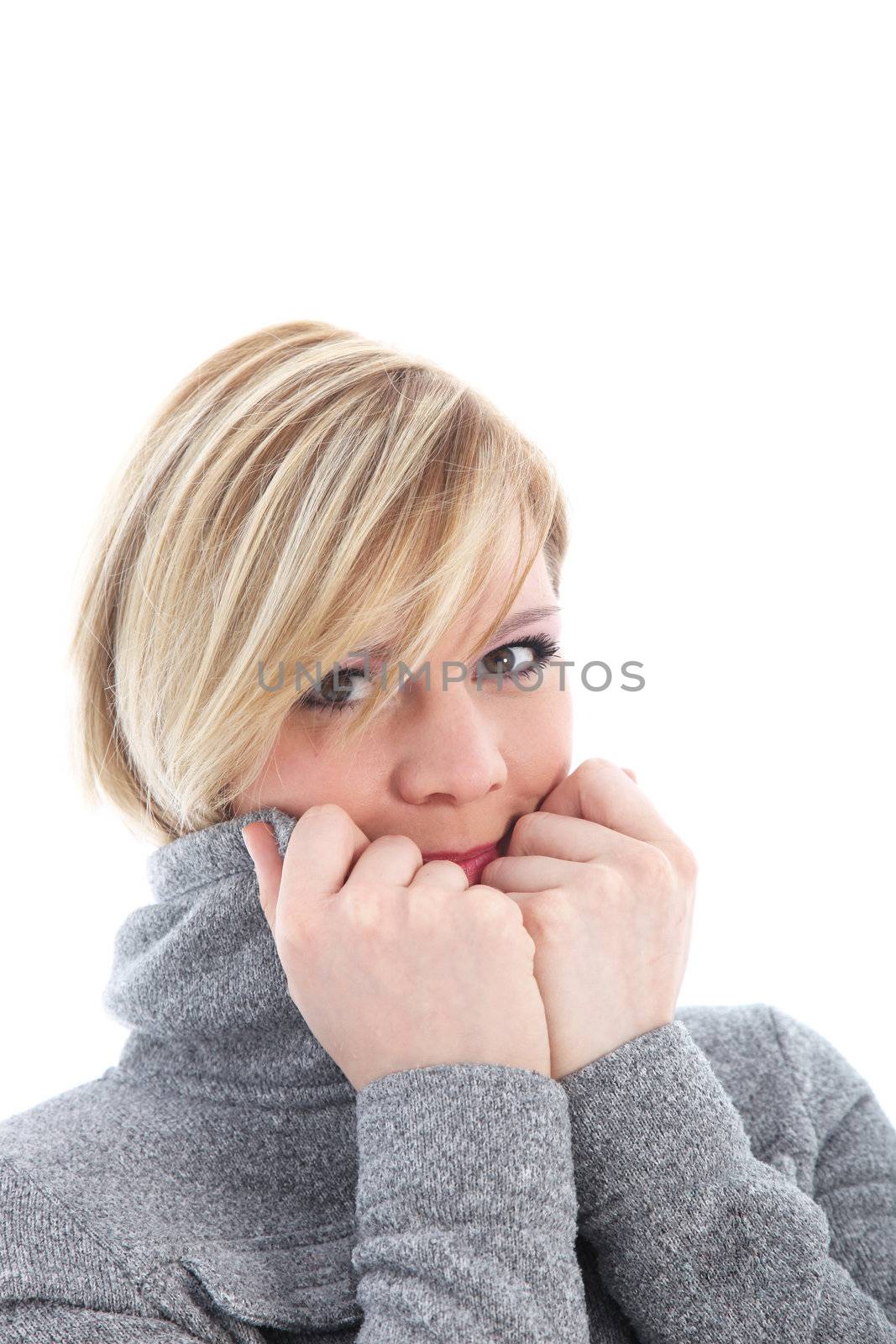 Woman shivering in the winter cold and pulling the collar of her jacket up close to her face in an effort to keep warm 