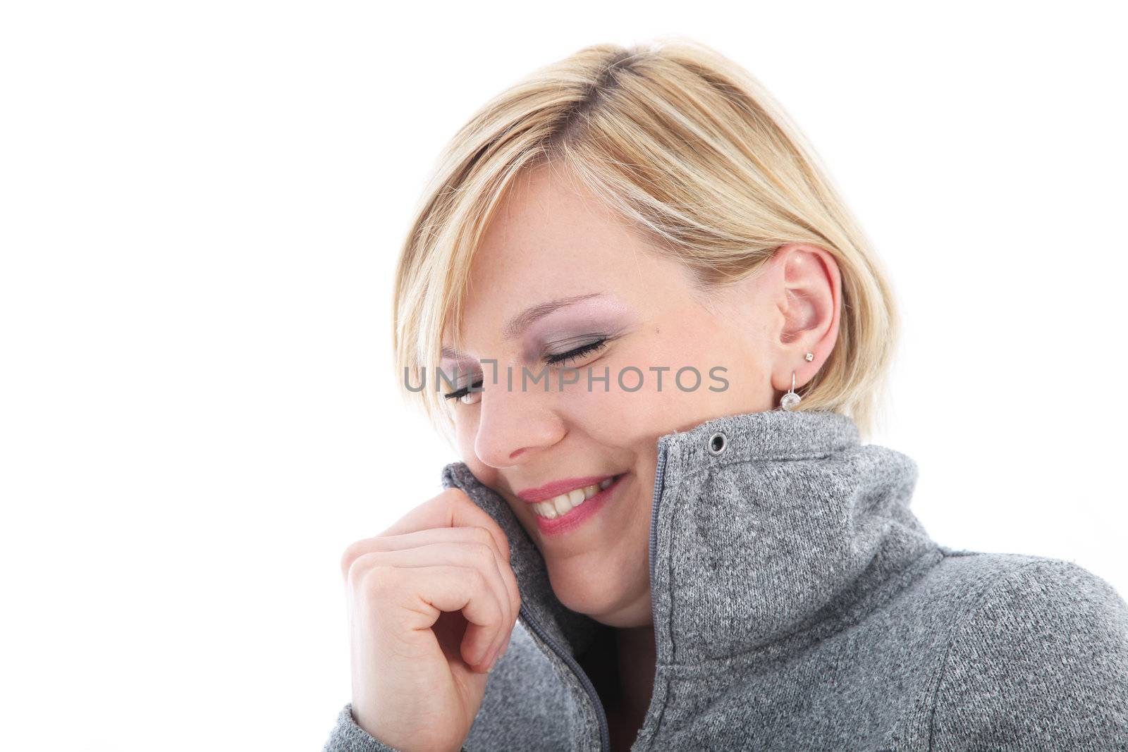Cold woman cuddling into her jacket smiling in appreciation at its warmth isolated on white Cold woman cuddling into her jacket smiling in appreciation at its warmth 