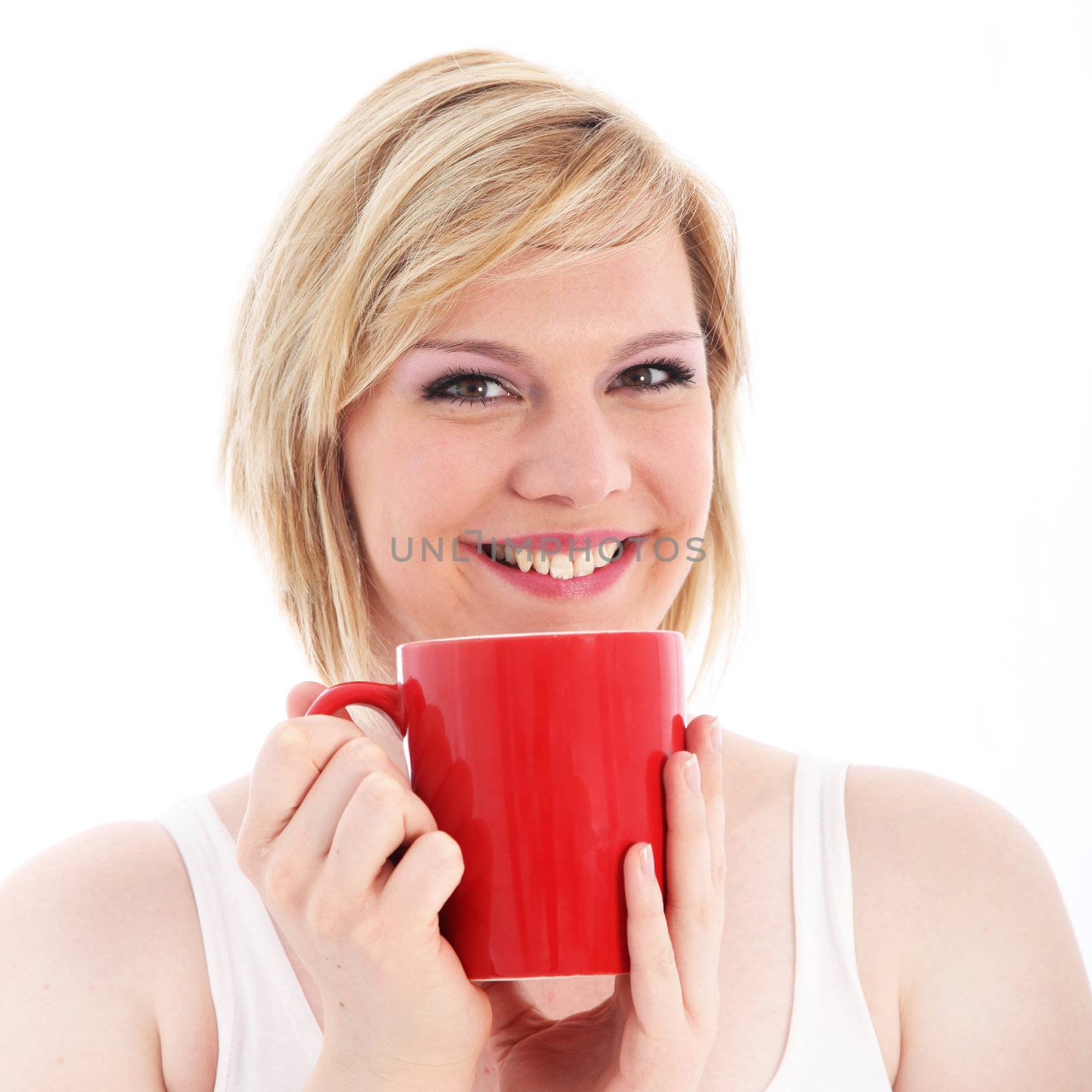 Happy woman smiling with pleasure as she nurses a large red mug of coffee in her hands 