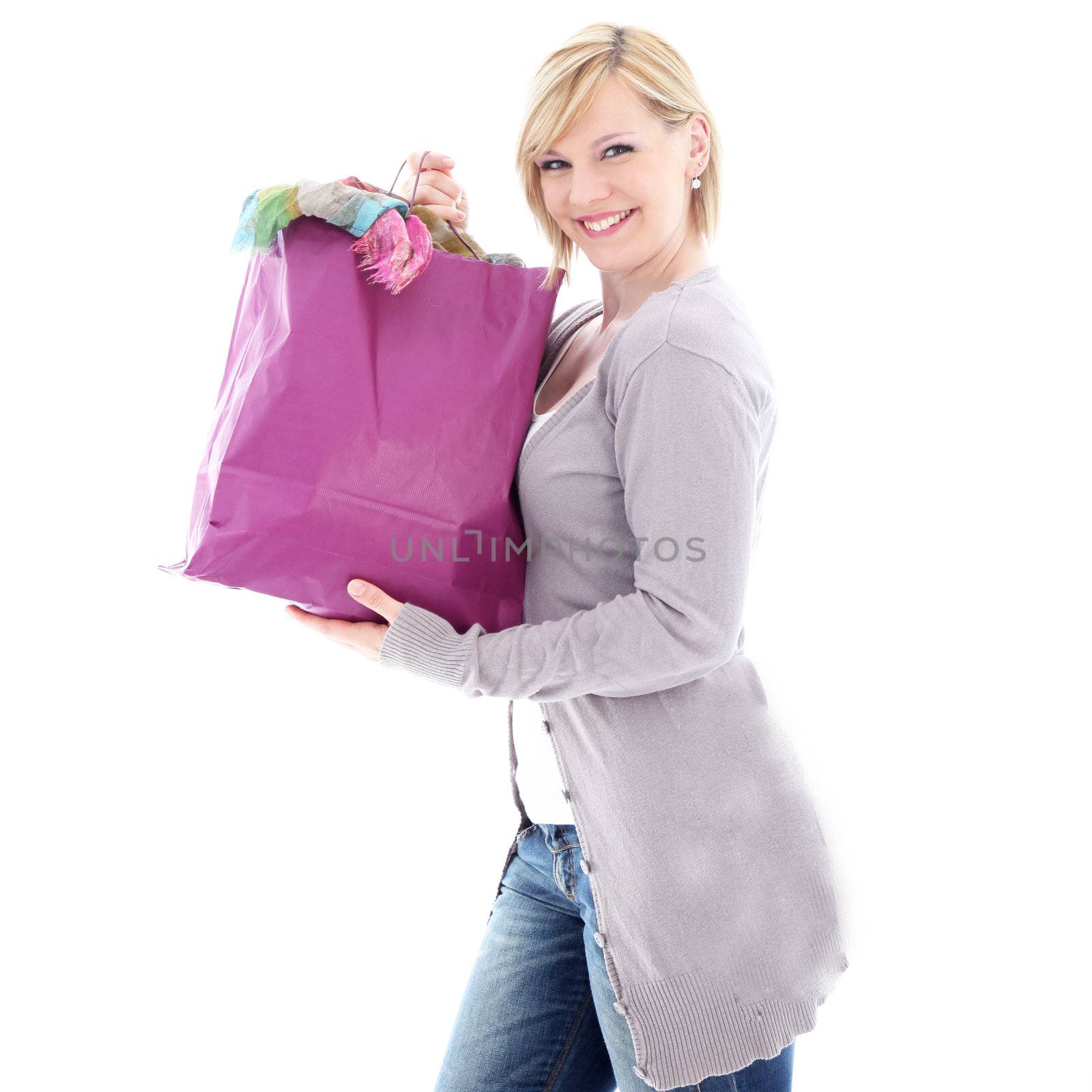 Happy woman smiling in glee after a successful shopping spree as she carries home a carrier bag crammed full of new clothing 