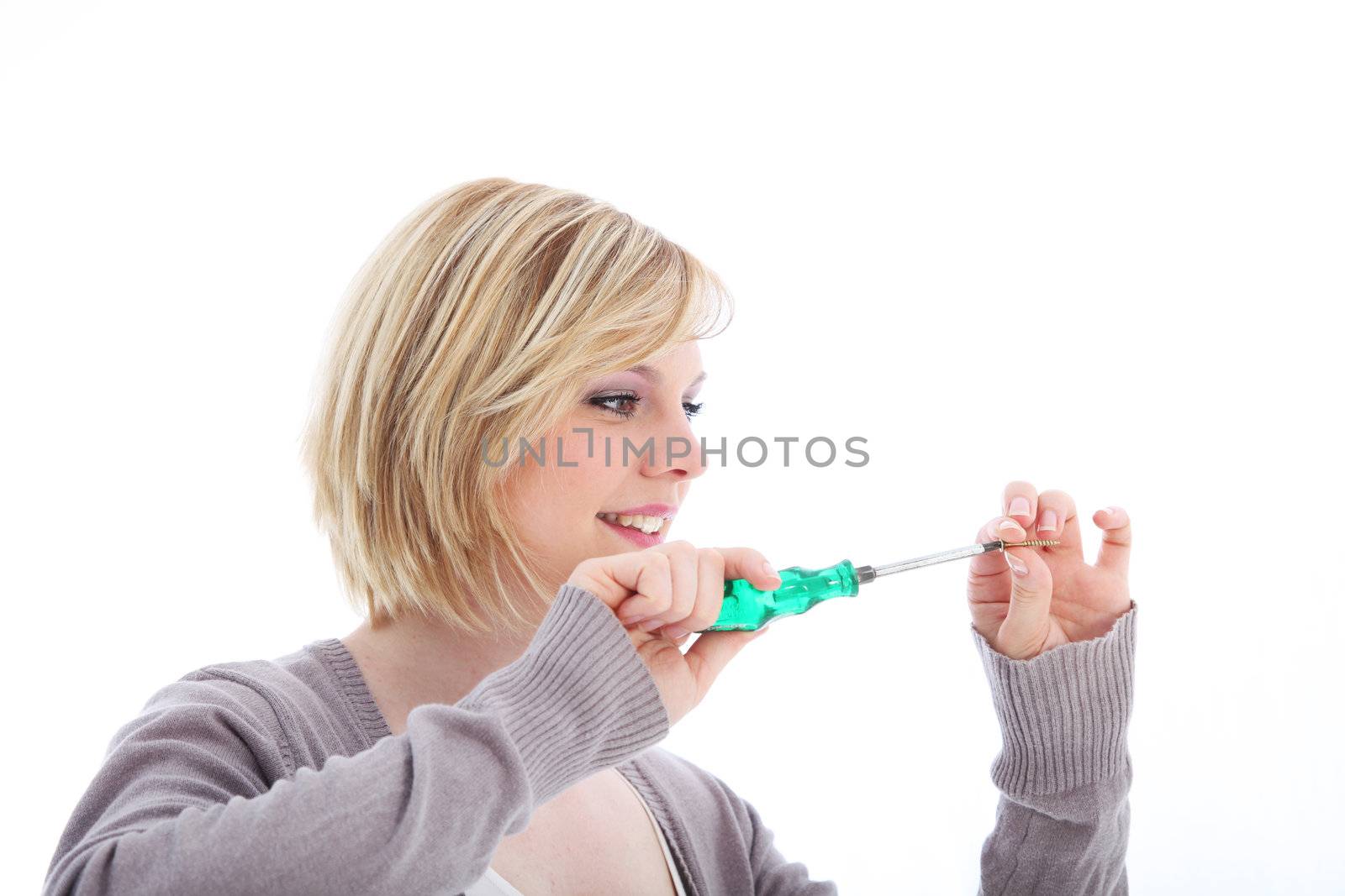 Woman working with a screwdriver fitting it into the head of a screw that she is holding between her fingers in a DIY concept 