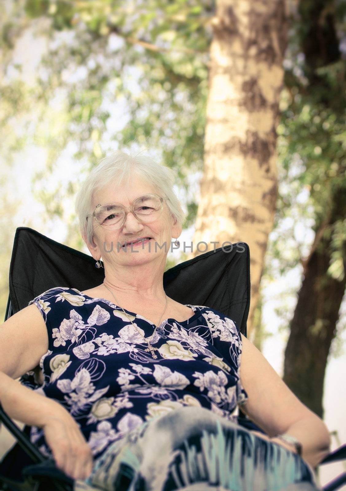 Senior lady sitting on chair in the nature