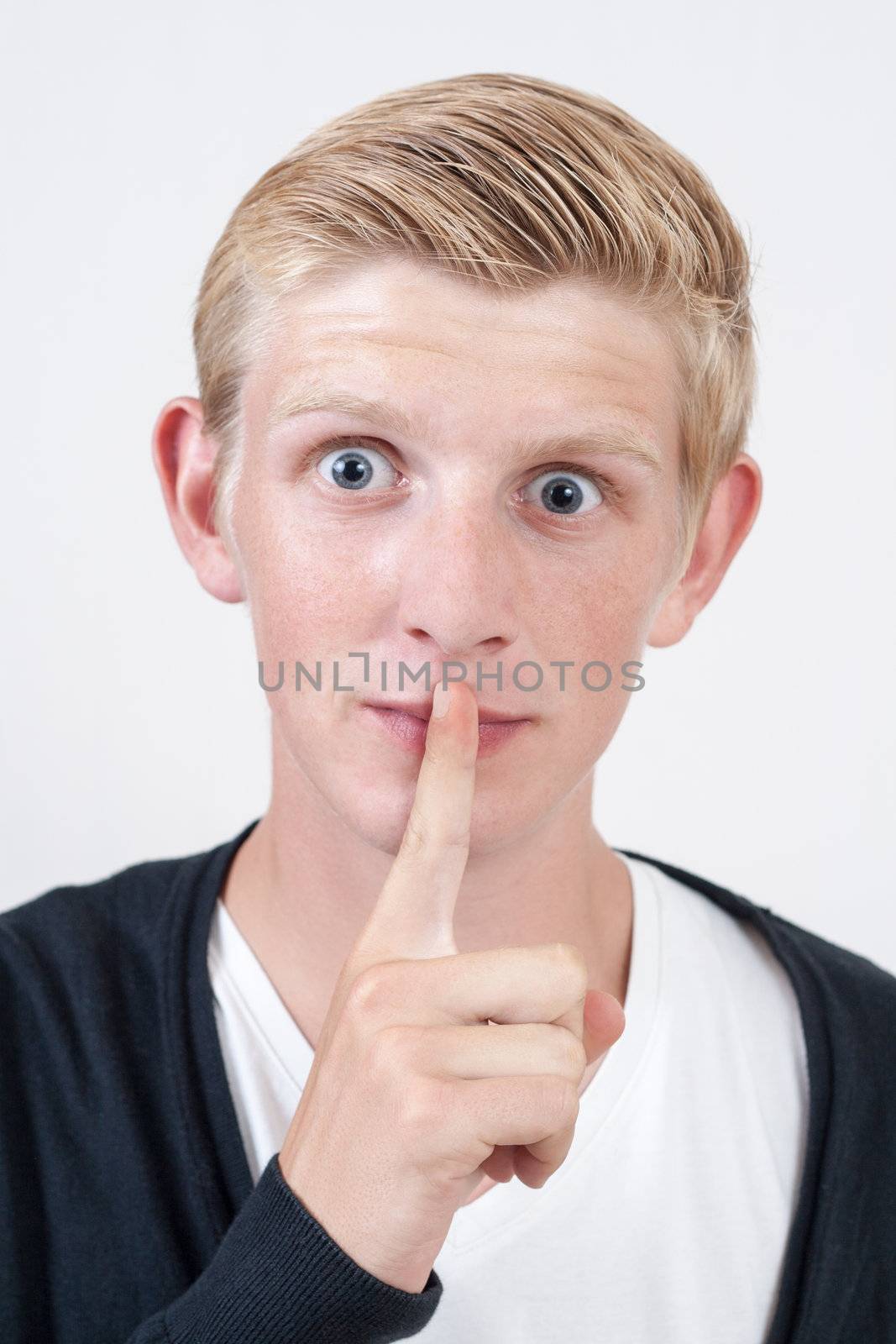 young blond man showing silence gesture, hand over mouth