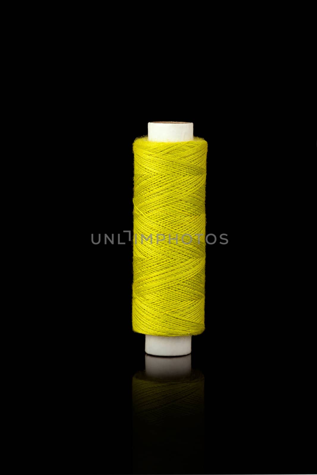 Yellow spindle of yarn isolated over black background