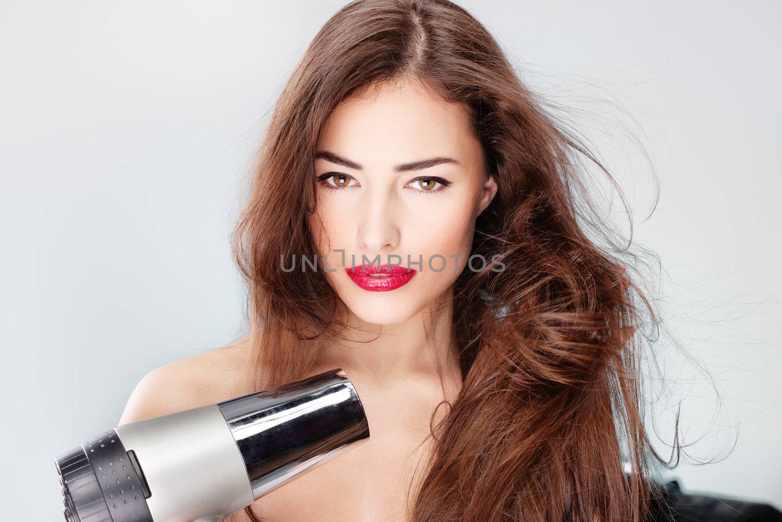 woman with long hair holding blow dryer by imarin