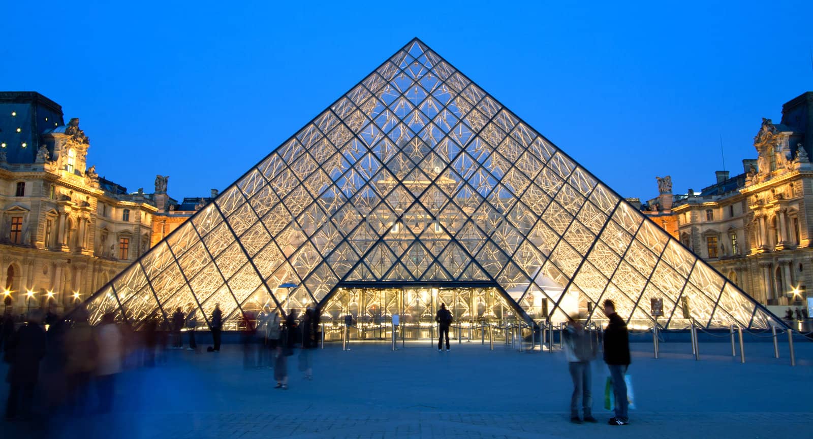 PARIS - APRIL 16: Crowd at entrance of Louvre pyramid at dusk during the Summer Exhibition April 16, 2010 in Paris. This is one of the most popular tourist destinations in France.