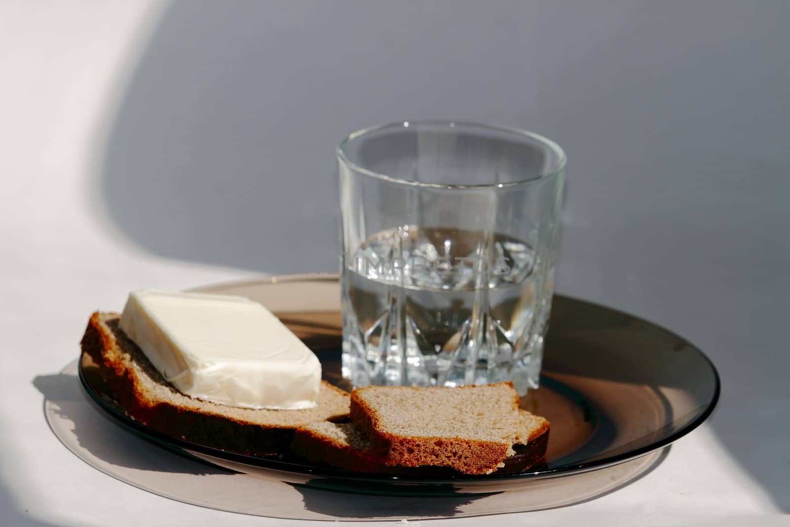 a glass of vodka and on a dark plate on a white background