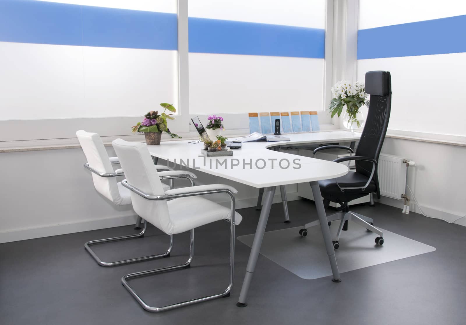 clean white office in hospital with flowers laptop and phone