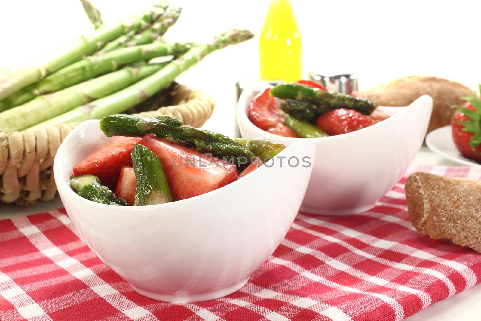 Asparagus salad with fresh strawberries, salt and pepper on a light background