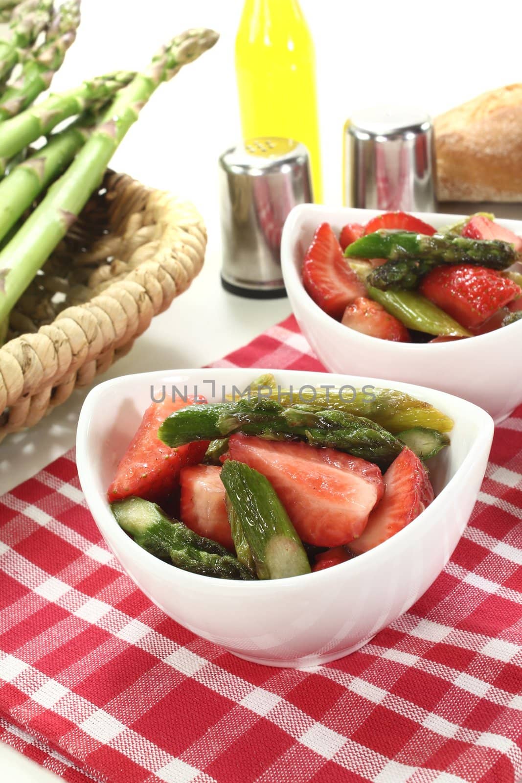 Asparagus salad with  strawberries, salt and pepper on a bright background