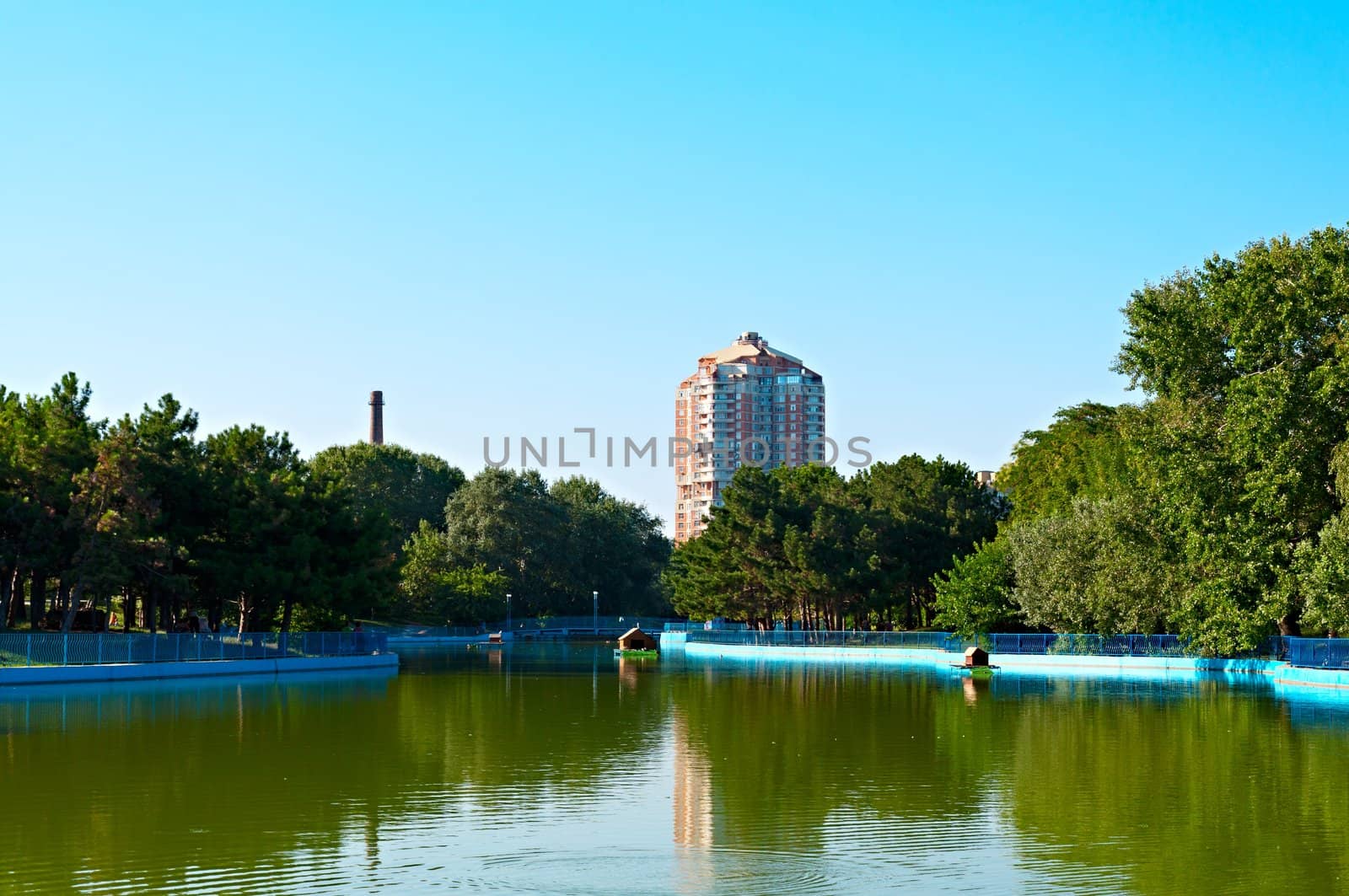 Landscape - a pond in the park Victory, Odessa, Ukraine and residential building in the background, the boiler house chimney opposite the house.