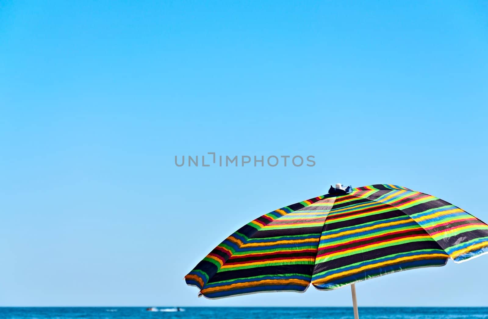 Colorful umbrella against the blue sky and the sea horizon