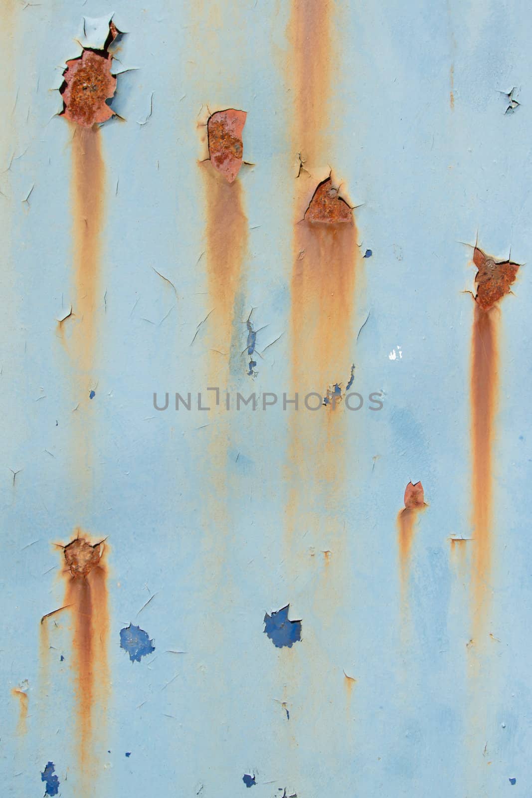 A metal plate with flaking blue paint in layers and patches of rust and orange streaks.