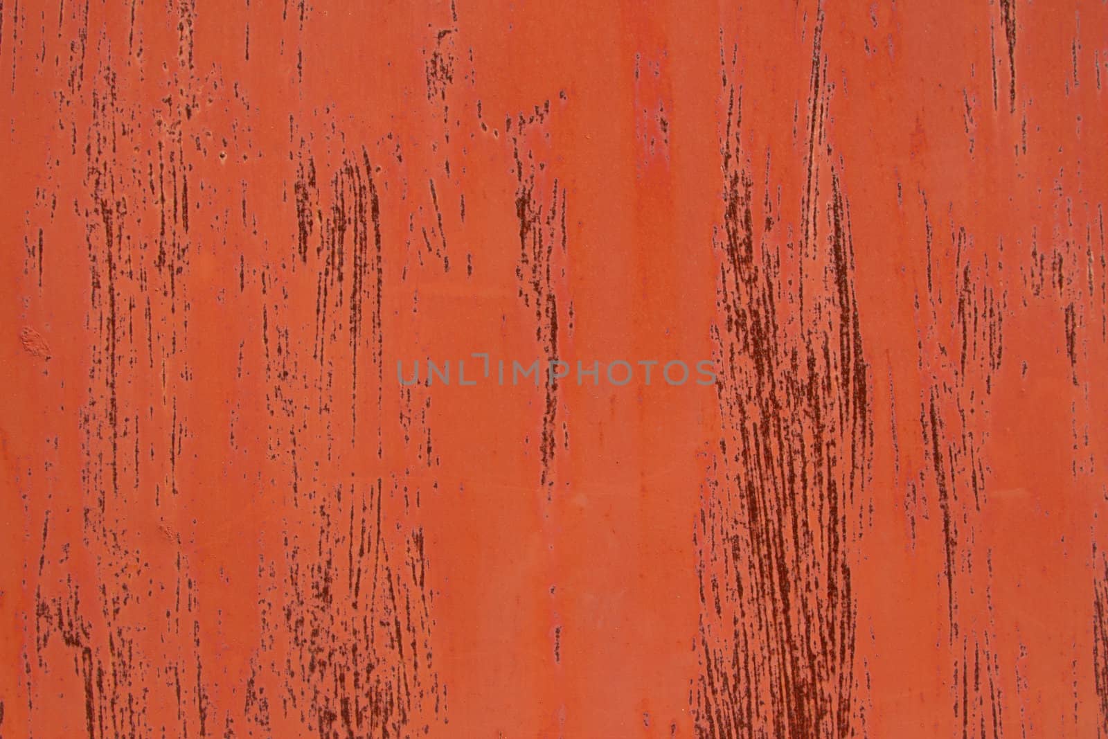 A metal base with orange paint and streaks over rust red.