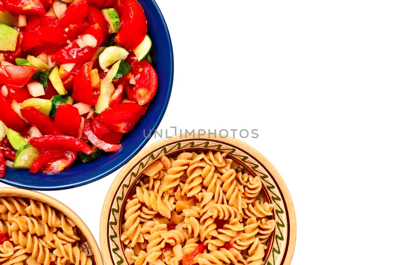 A bowl of salad and two plates with pasta with tomatoes, isolated on white background
