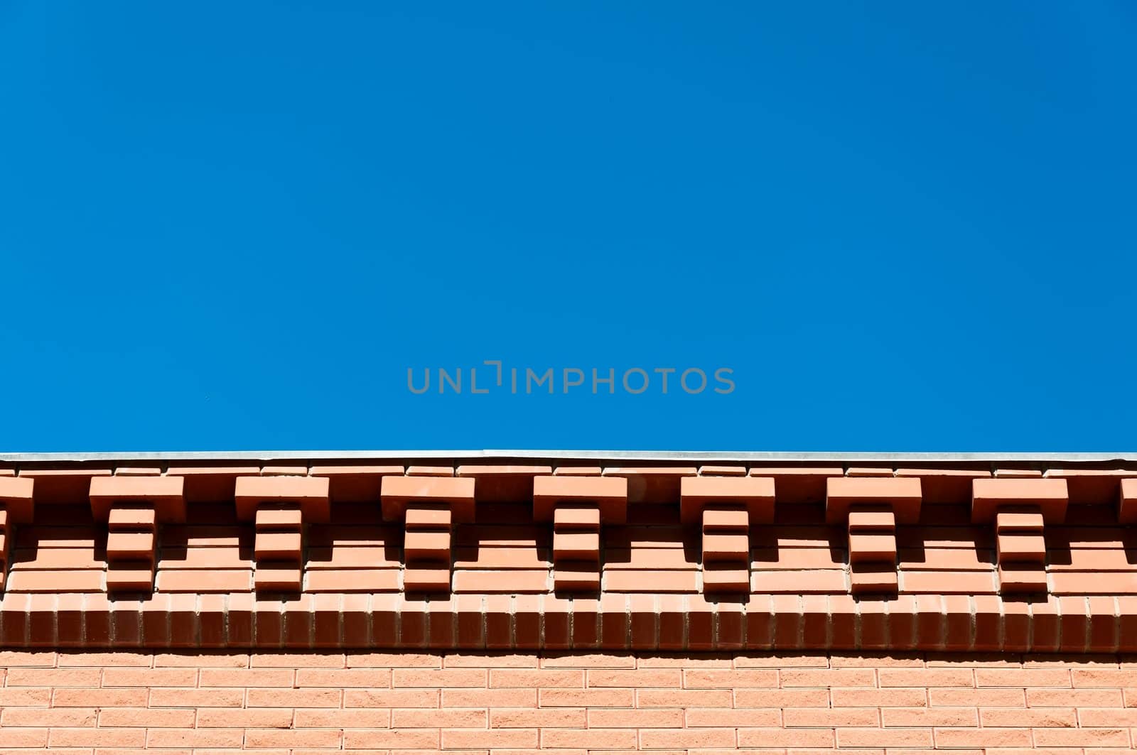 Decorative eaves from a red brick against the blue sky.