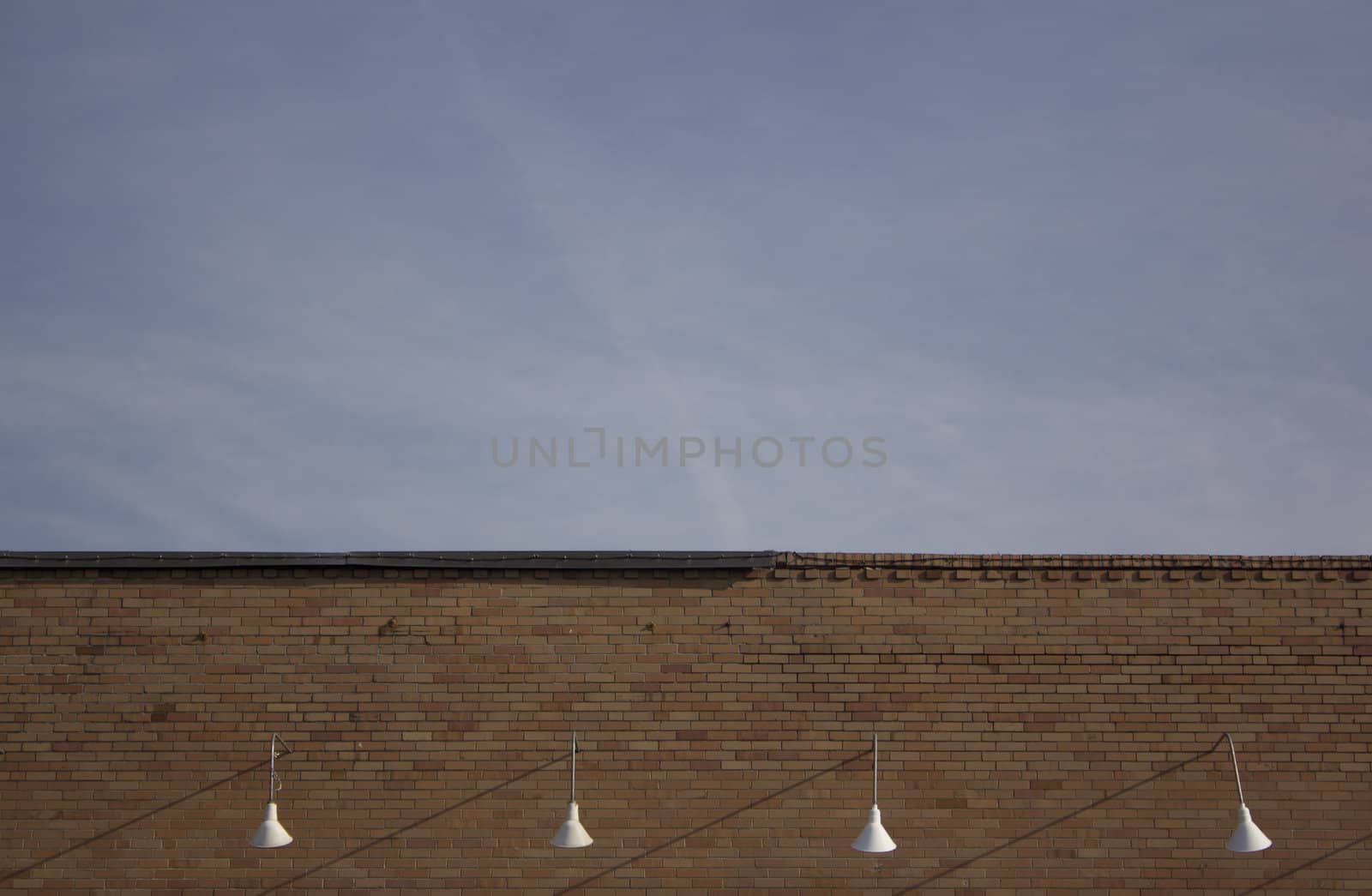 exterior store front lights with a brick wall and blue skies.
