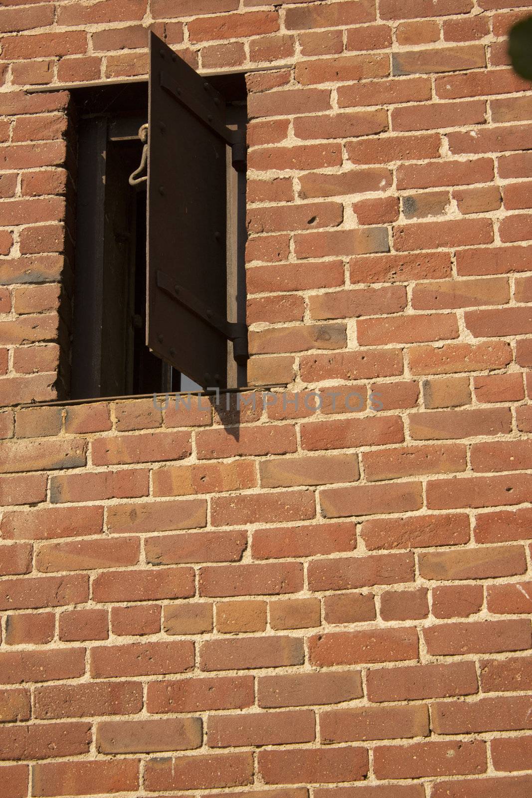 an old rusty window in a brick wall. the side of an old western jail.
