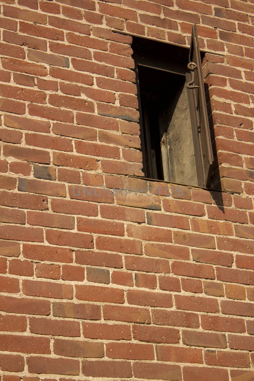 an old rusty window in a brick wall. the side of an old western jail.