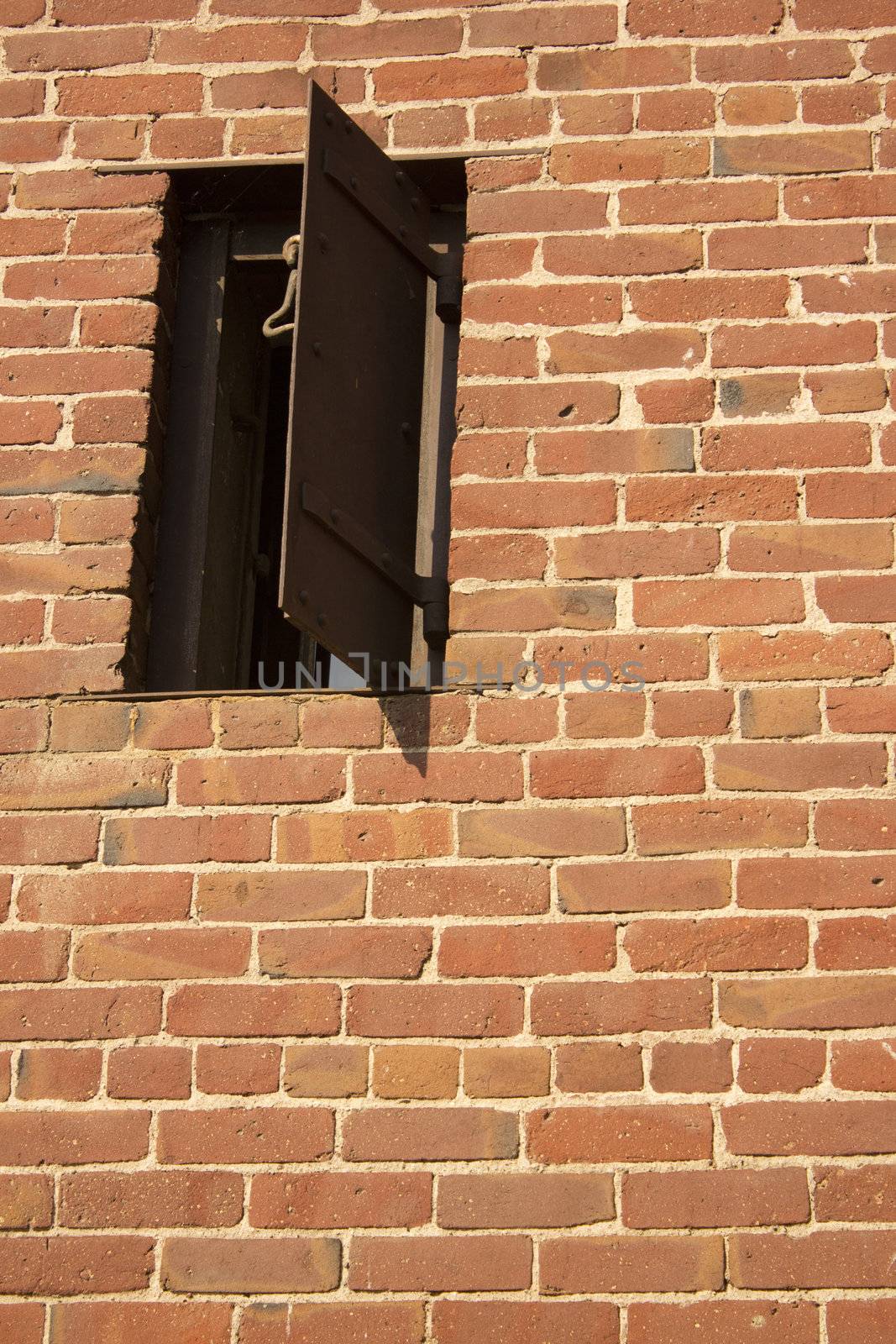 an old rusty window in a brick wall. the side of an old western jail.