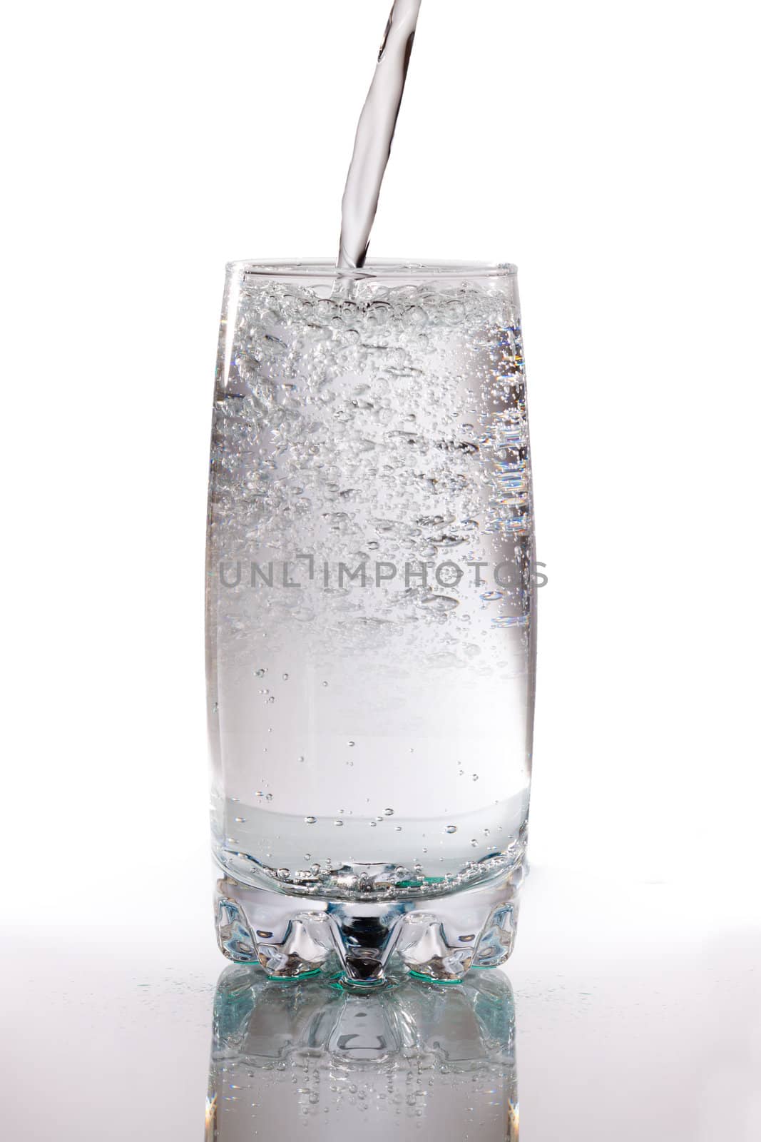 Mineral water poured in to a glass on a white background