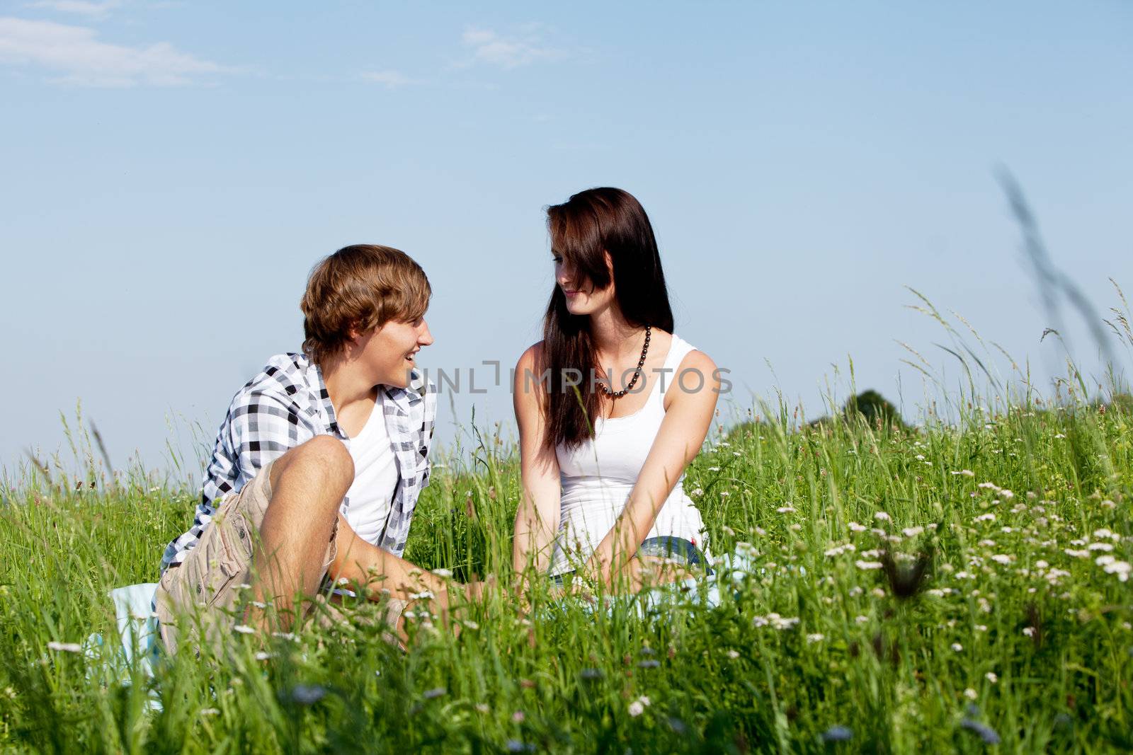 young couple outdoor in summer on blanket in love by juniart
