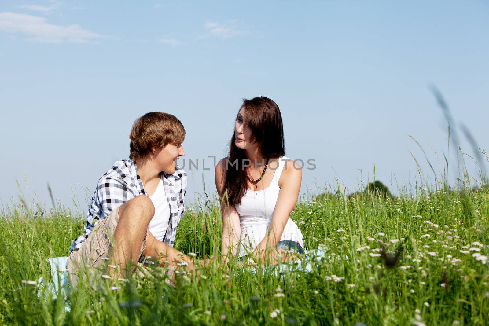 young couple outdoor in summer on blanket in love by juniart