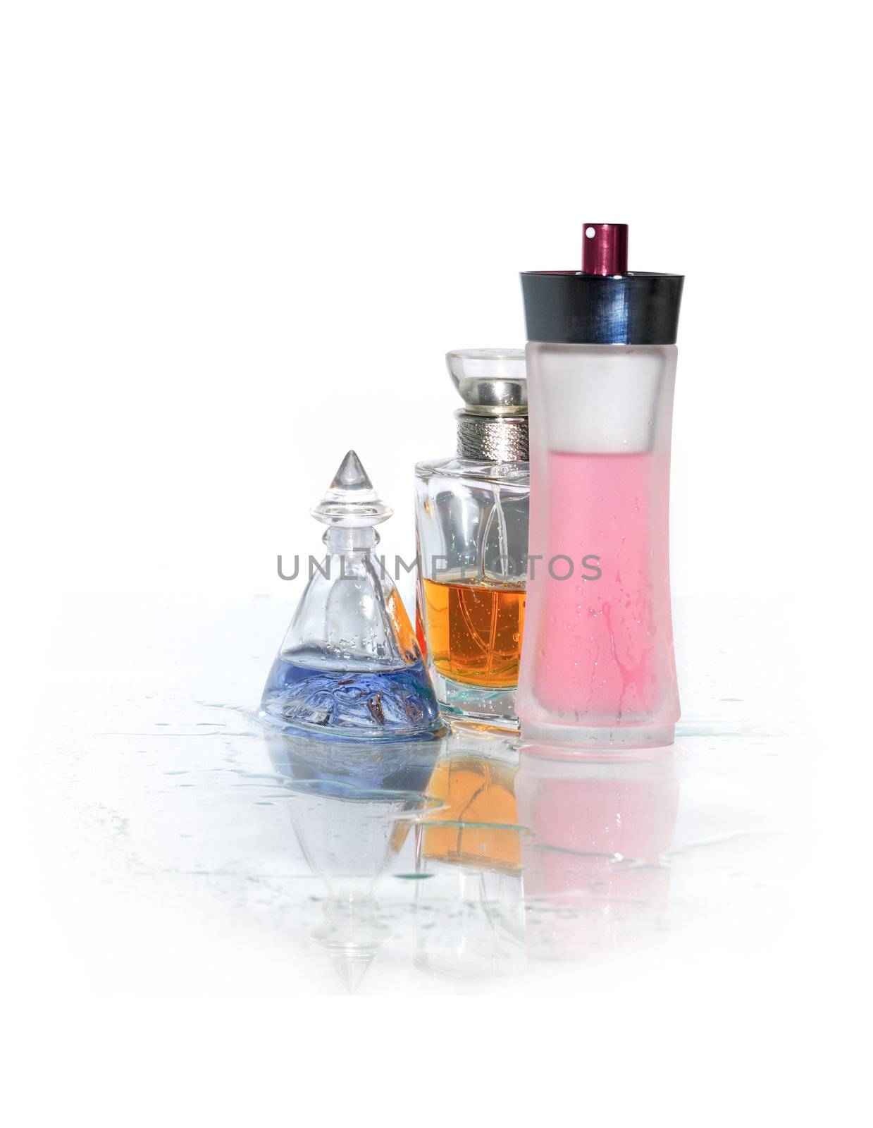 Three bottles of perfume standing on wet glass surface. Clipping path is included