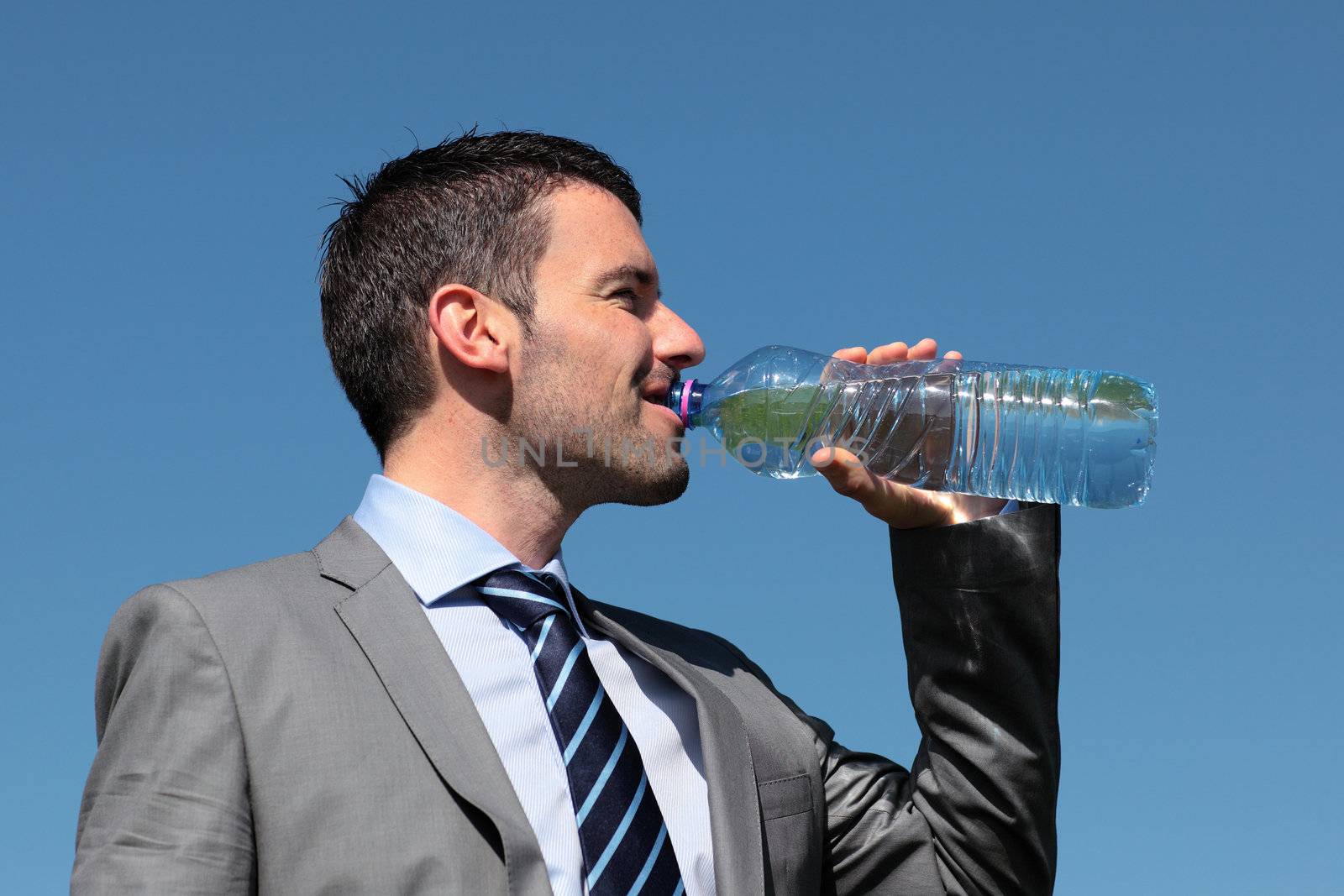 businessman drinking water with bottle and blue sky