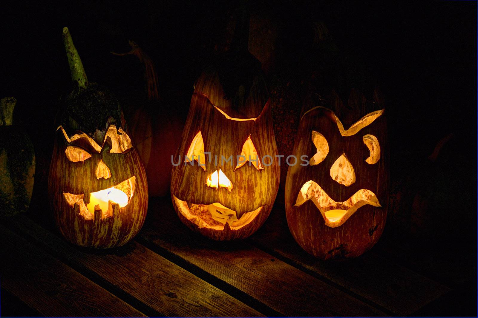 HDR image of carved eggplant jack o'lanterns on a small table in the dark for the halloween holiday