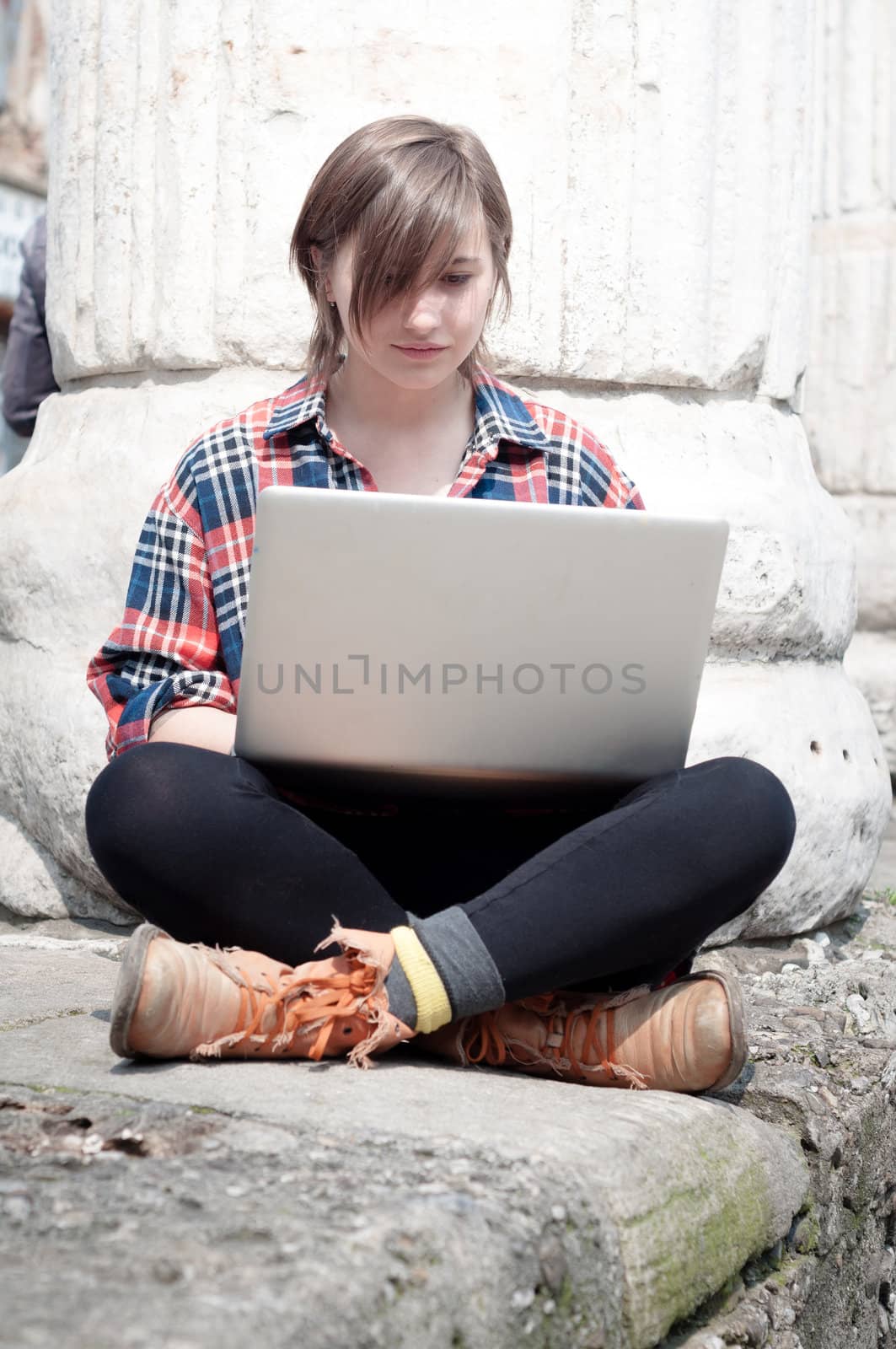 young woman using notebook in the street