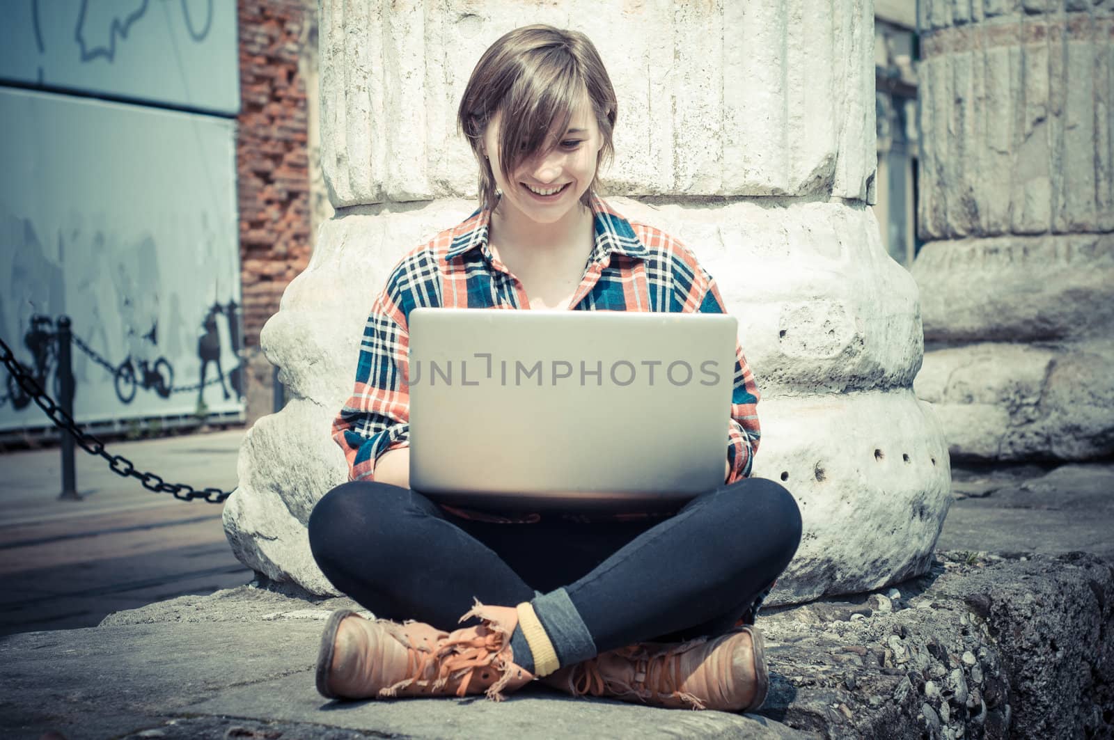 young woman using notebook in the street