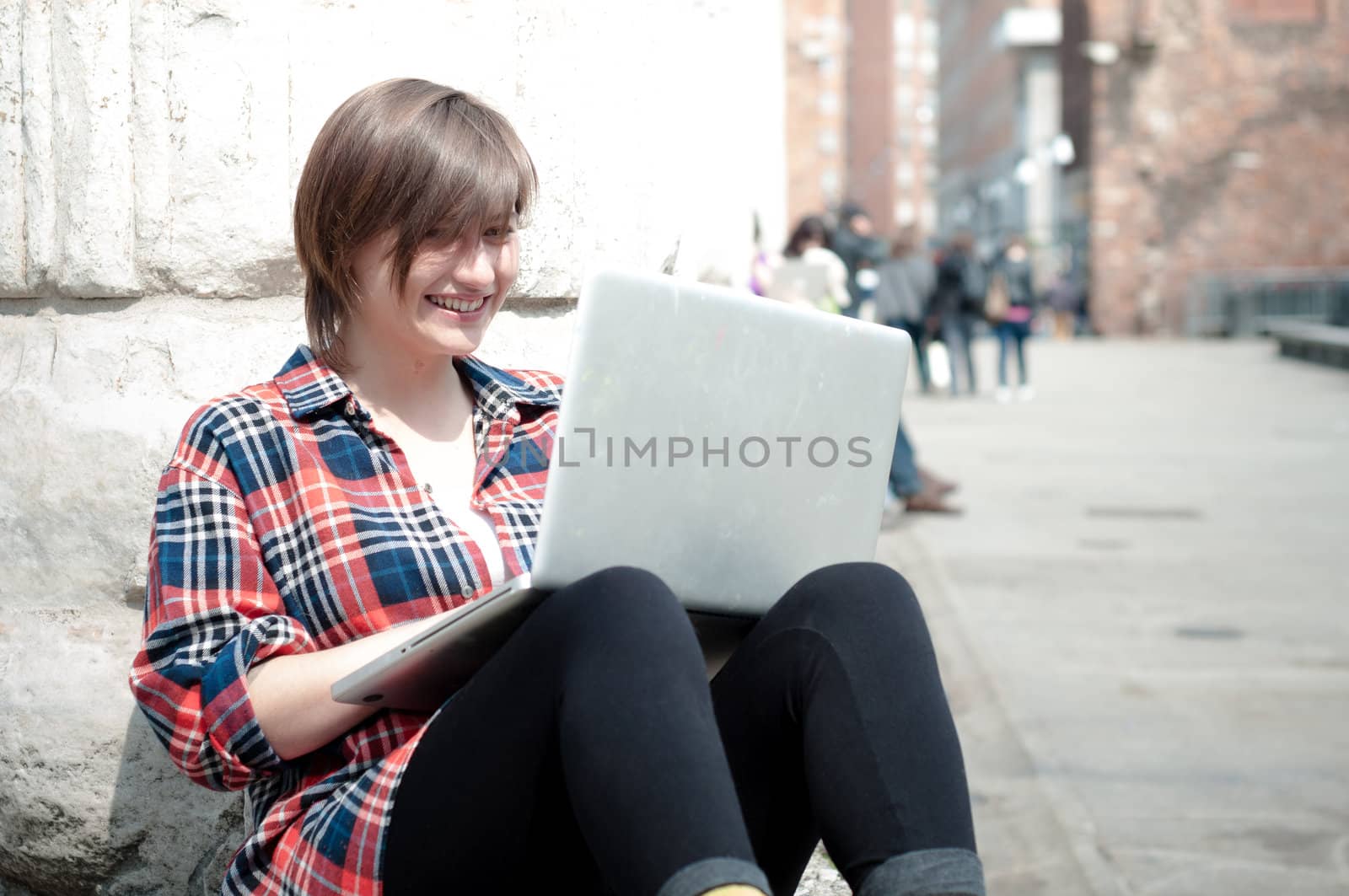 young woman using notebook in the street