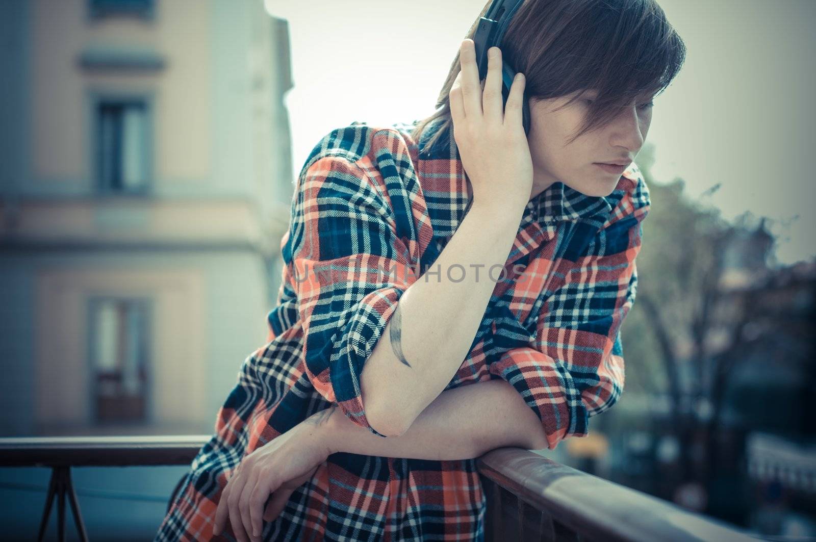 young hipster woman listening to music on balcony