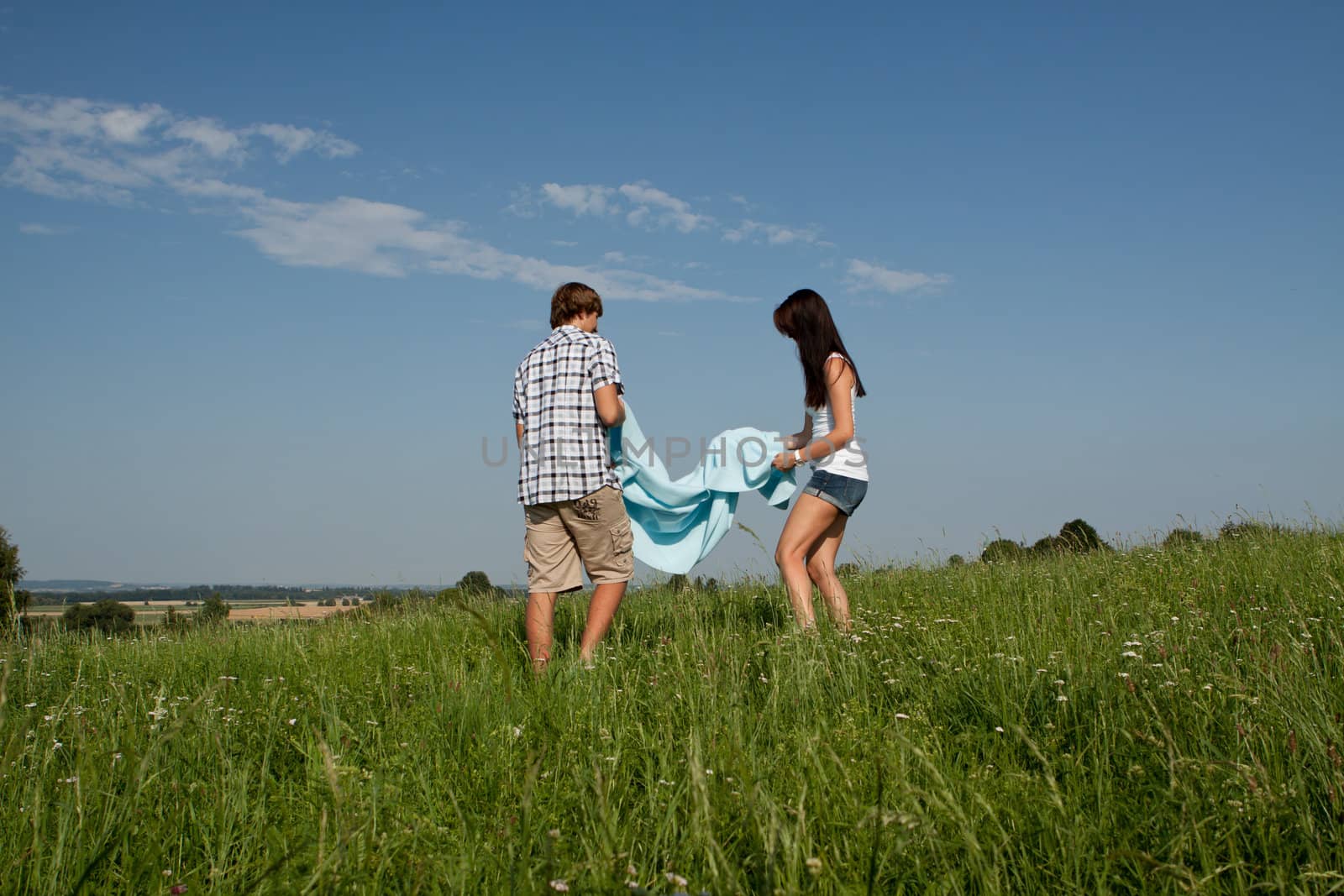 young couple outdoor in summer on blanket in love by juniart