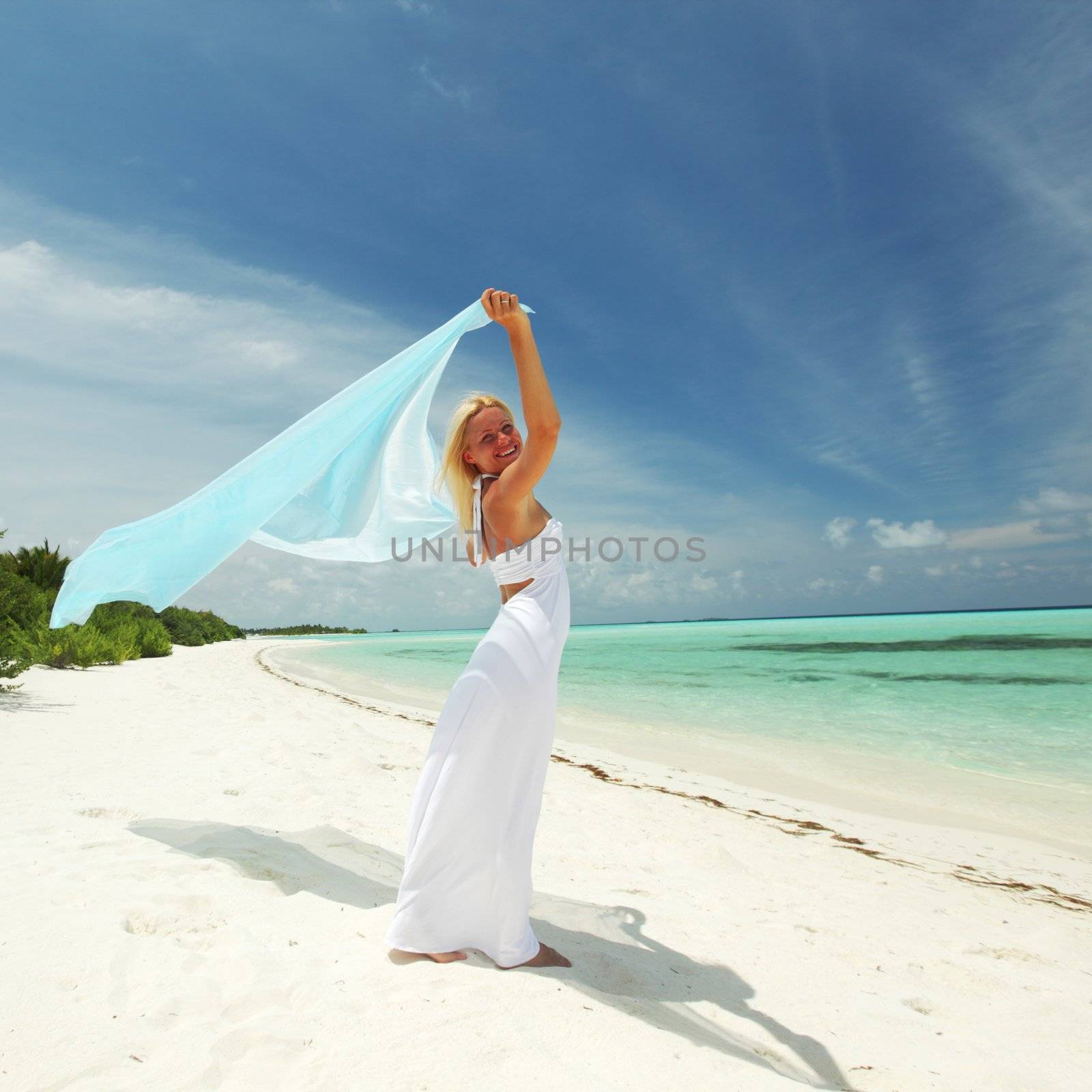 woman with a white fabric in his hands on the beach