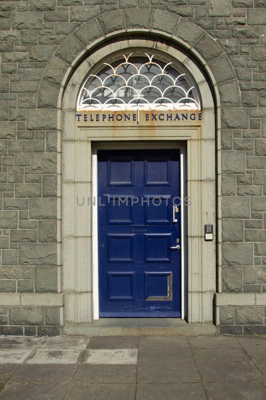 A doorway with blue door, arch  with a keypad and sign with the words 'TELEPHONE EXCHANGE'.