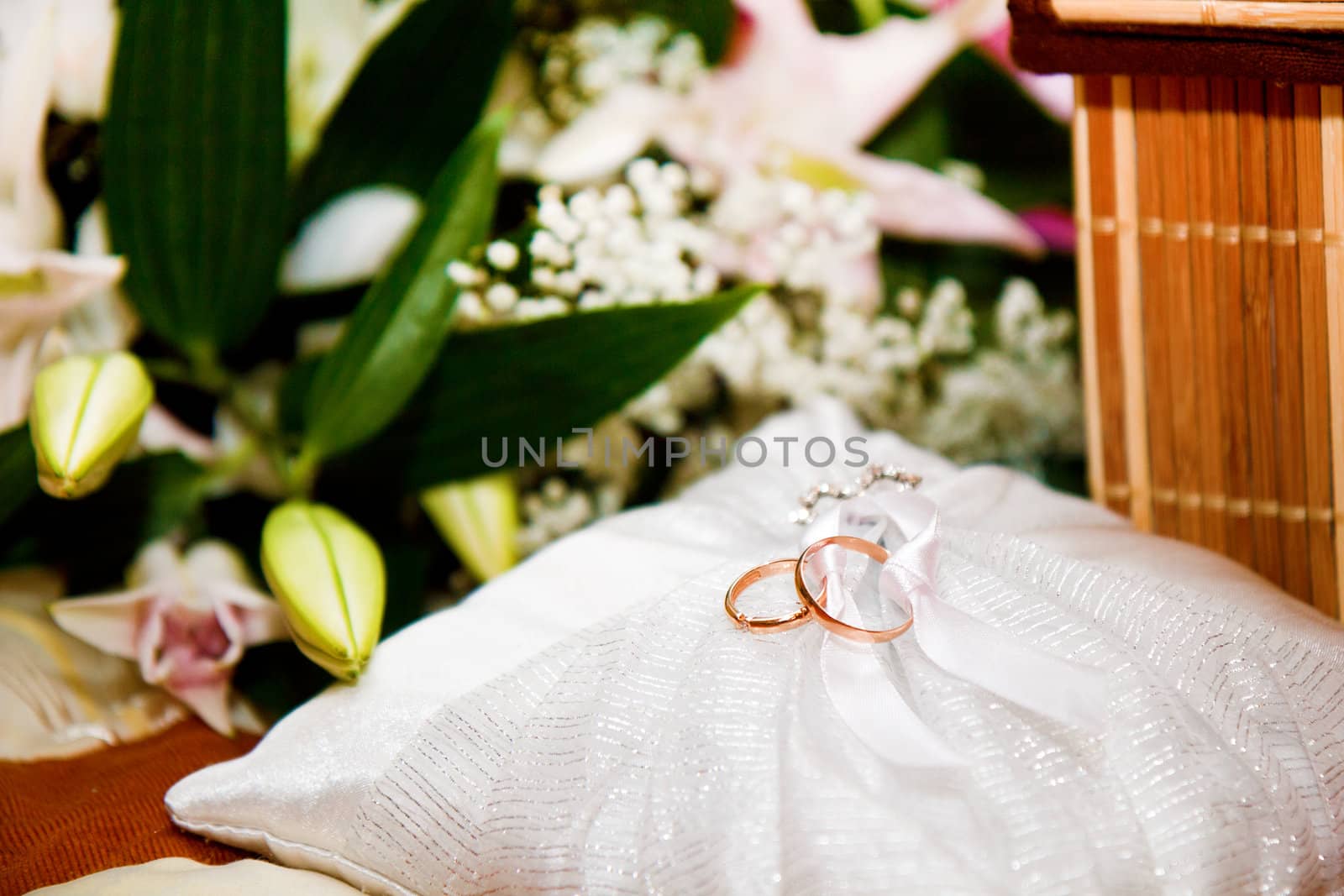 pillow with wedding rings on a background of a bouquet