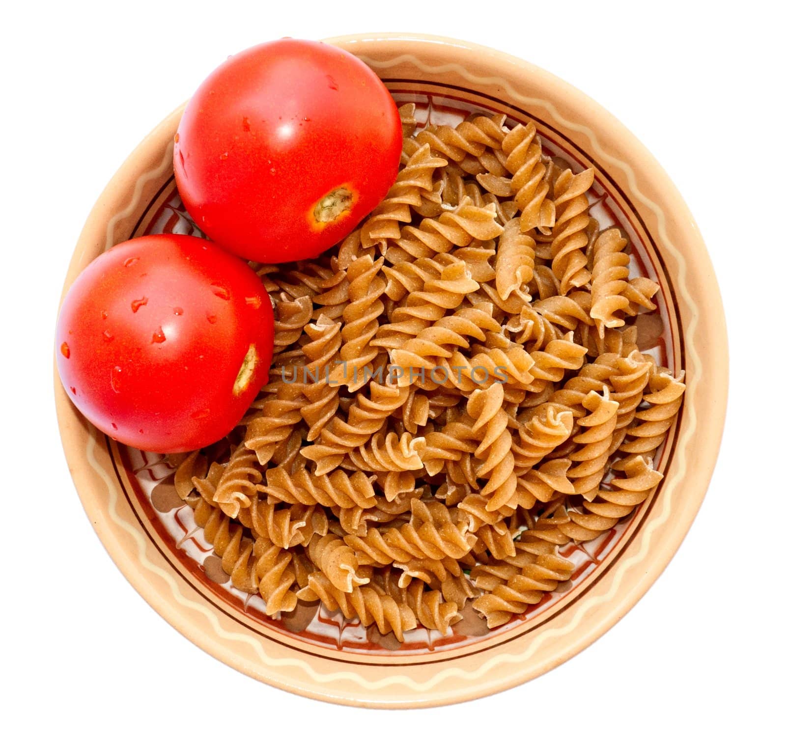 Deep dish with raw wholemeal pasta and fresh tomatoes, isolated on a white background, top view.