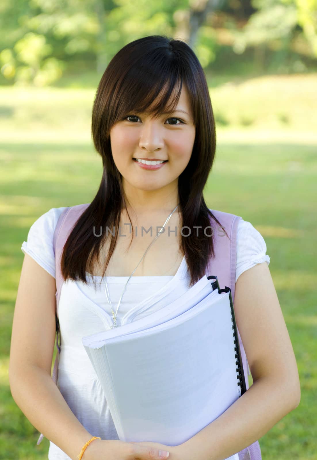 College student standing outside campus, green park