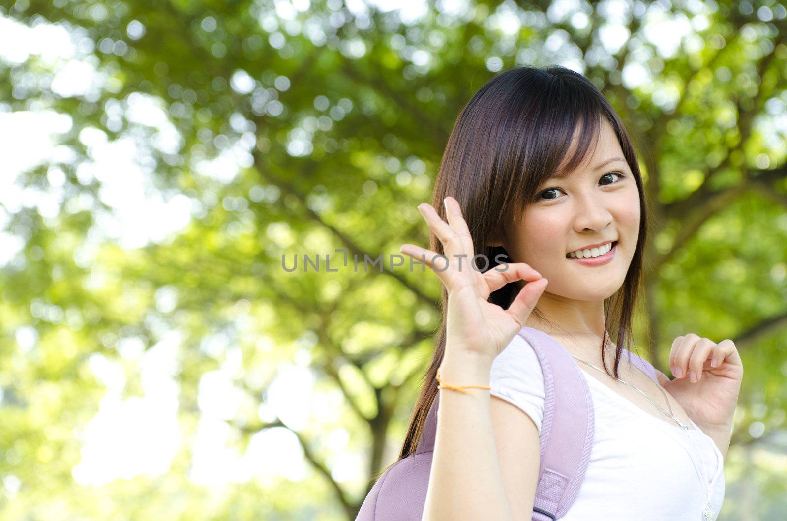 Cheerful Asian college student giving a okay hand sign