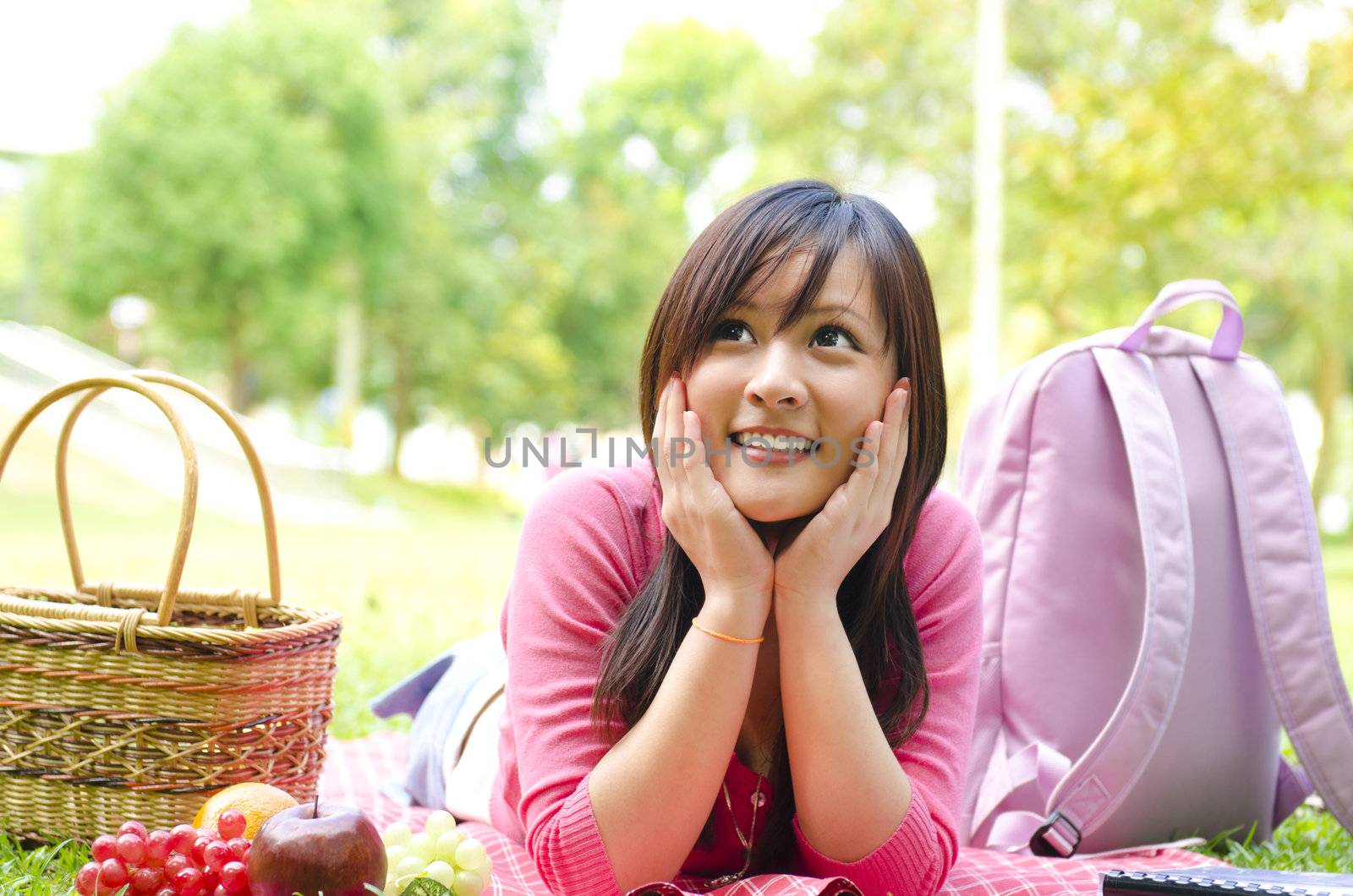 Young Asian student studying on campus lawn