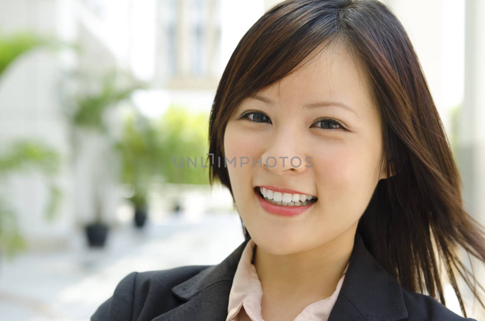Asian female with her cheerful smile, outside modern building.
