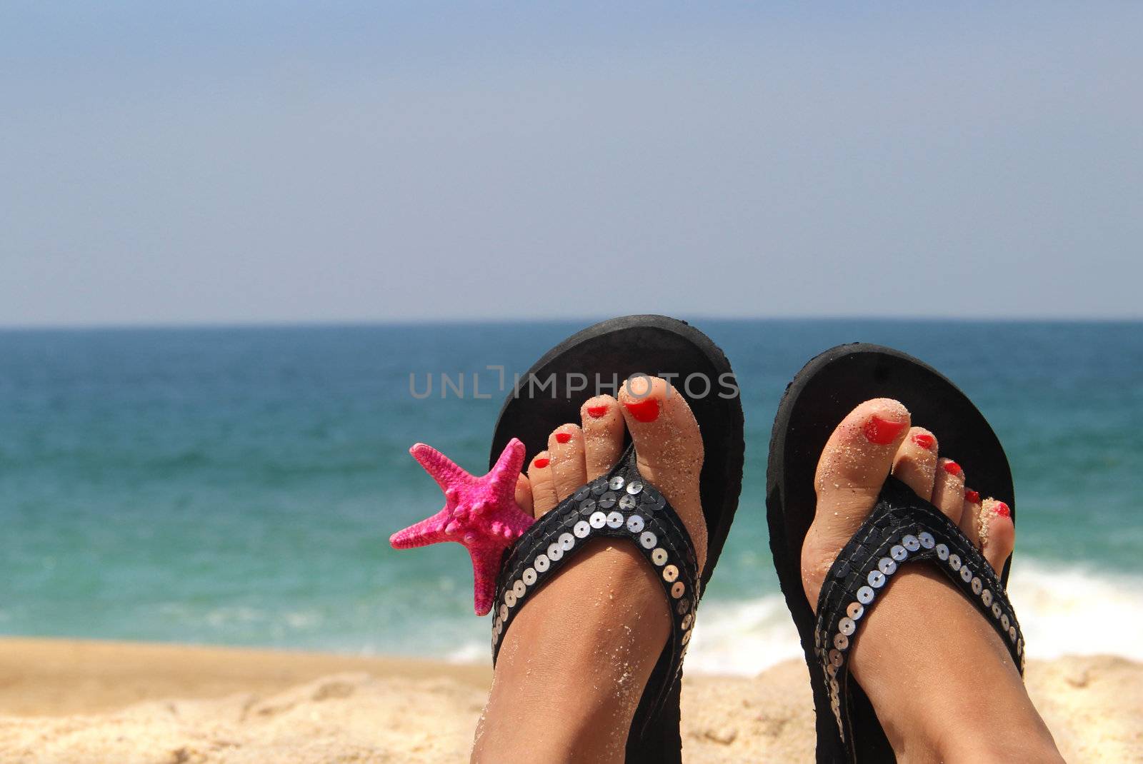 Relaxation on the beach - female feet decorated with sea star