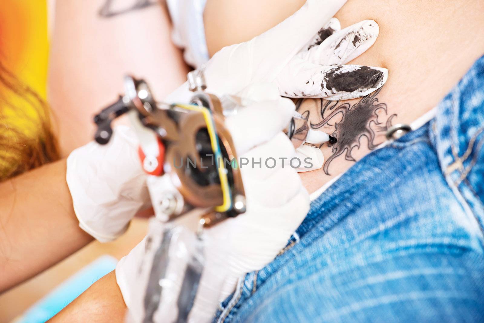 hands of a tattoo artisan making art on belly