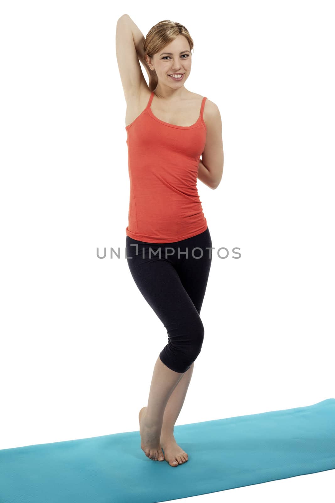 young fitness woman standing on a mat stretching her arms by RobStark