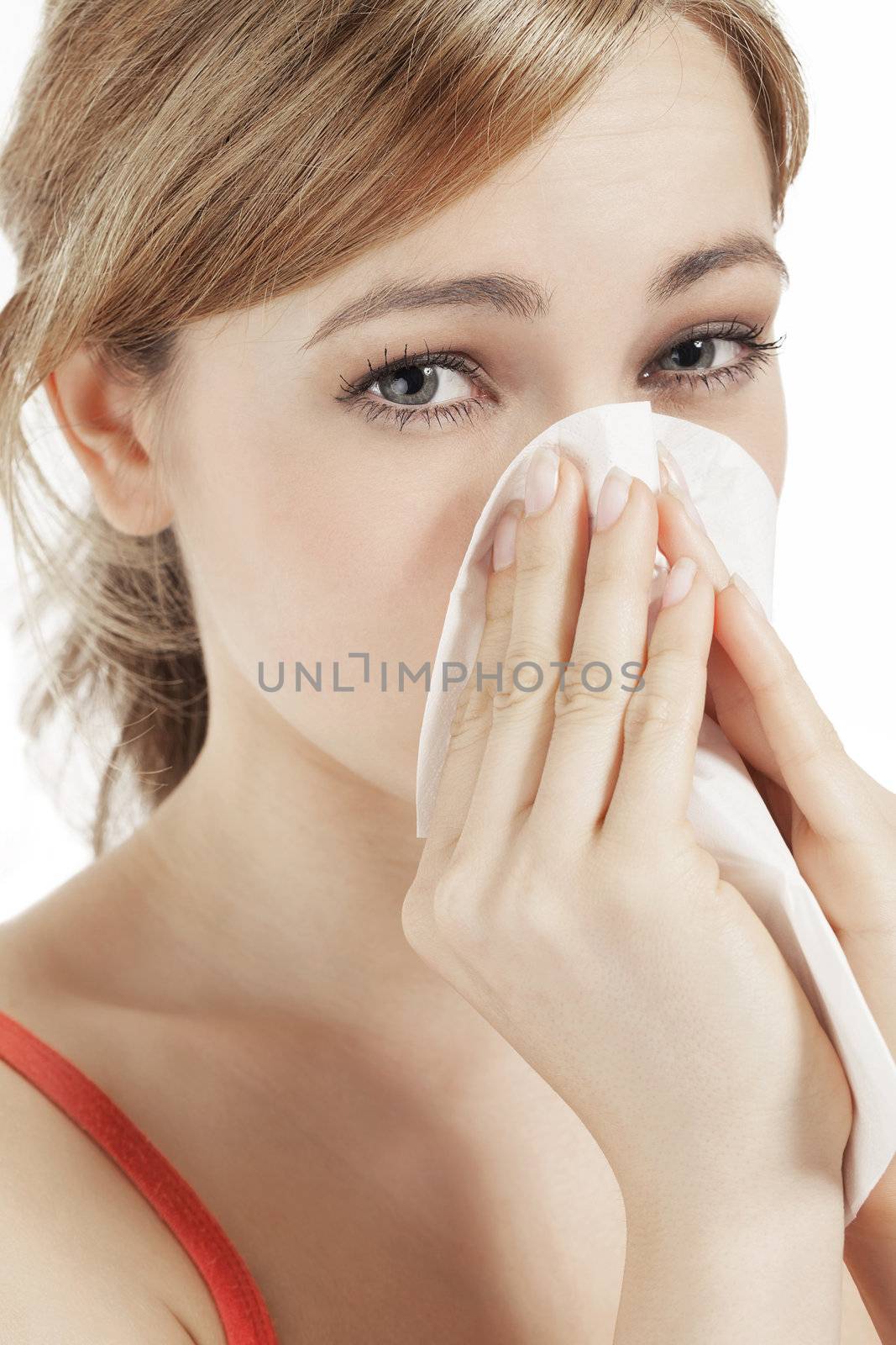 young blonde woman suffering on hay fever sneezing with a paper tissue